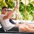 A man and a woman on lounge chairs next to a pool waving