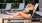 A man and a woman on lounge chairs next to a pool smiling
