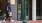 A man and a woman walking on a sidewalk next to a street light pole