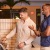 Two men smiling while they use a outdoor grill station