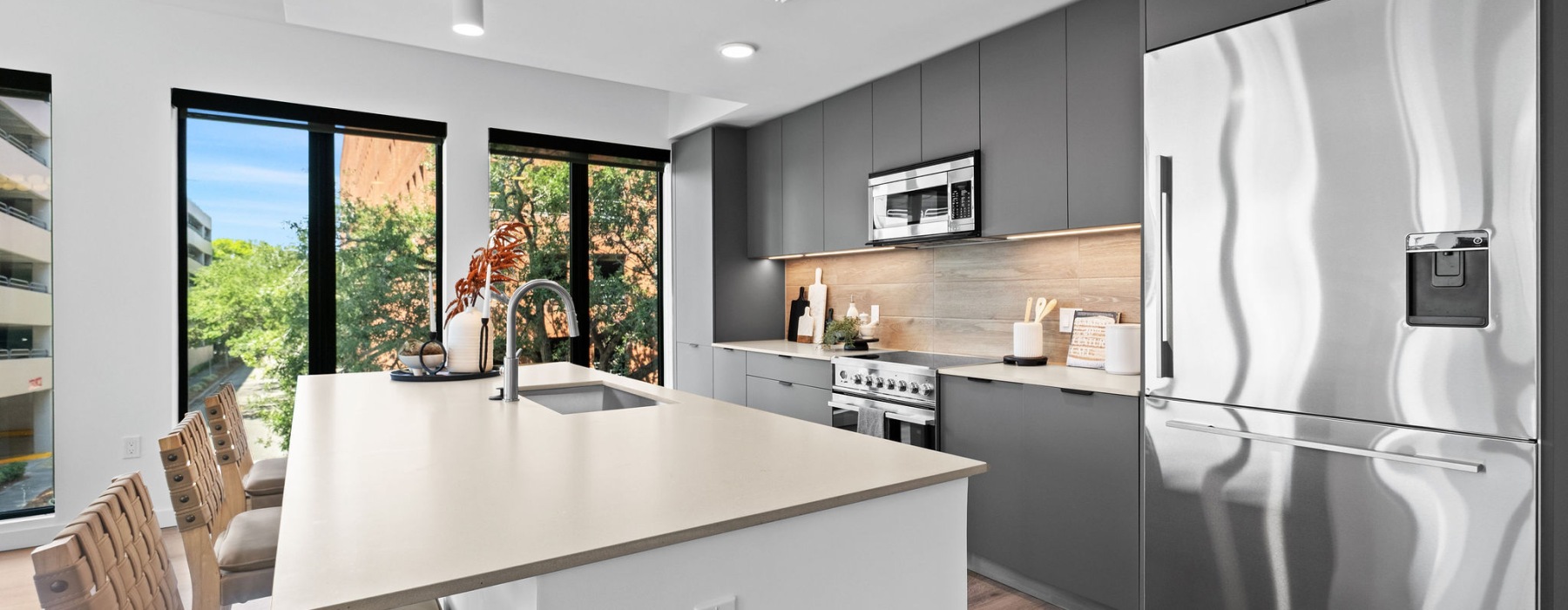 image of kitchen featuring stainless steel appliances, grey cabinetry and light countertops