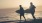 a couple on the beach carrying surf boards