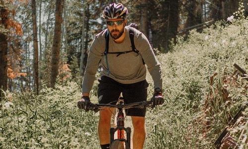 a man riding a bicycle on a trail in the woods